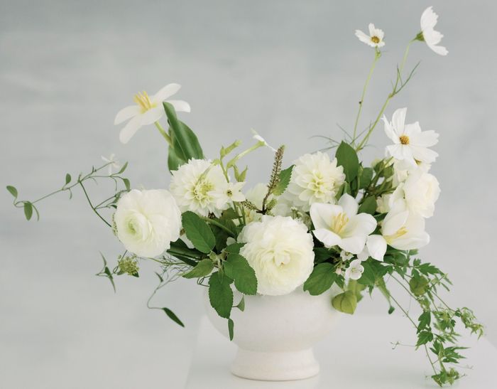 A white garden arrangement of roses, cosmos and fresh greens